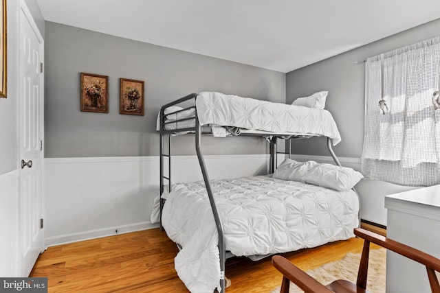 bedroom with a wainscoted wall and wood finished floors