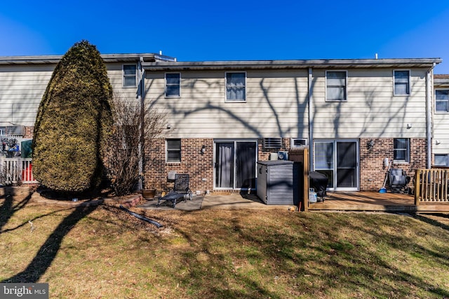 rear view of house with a patio, brick siding, and a lawn