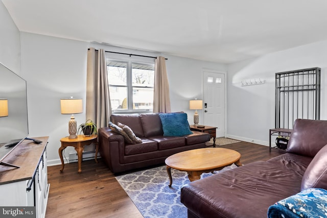 living area with a baseboard heating unit, wood finished floors, and baseboards