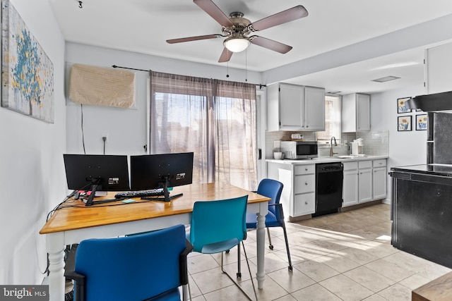 kitchen with a sink, decorative backsplash, light countertops, black dishwasher, and stainless steel microwave