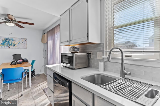 kitchen featuring a sink, light countertops, black dishwasher, stainless steel microwave, and tasteful backsplash