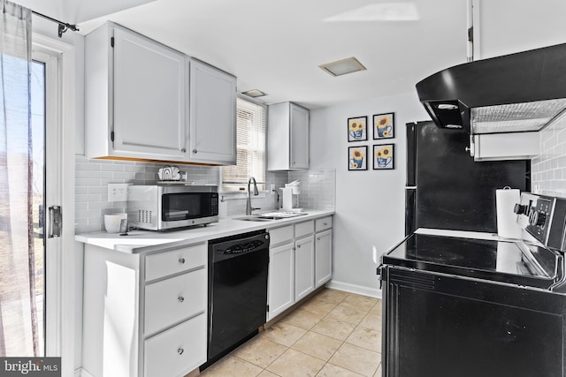 kitchen with a sink, black appliances, light countertops, under cabinet range hood, and tasteful backsplash