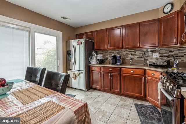 kitchen with stainless steel appliances, light countertops, visible vents, and decorative backsplash