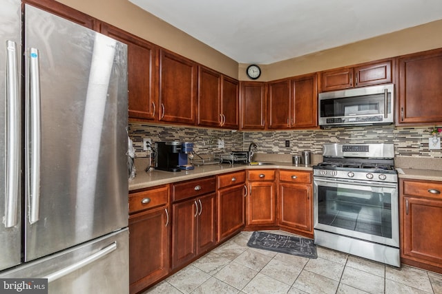 kitchen with stainless steel appliances, light tile patterned flooring, light countertops, and decorative backsplash