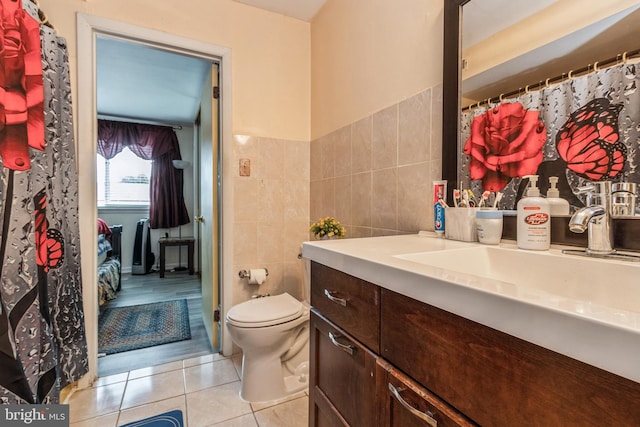 bathroom featuring toilet, vanity, tile patterned flooring, and tile walls