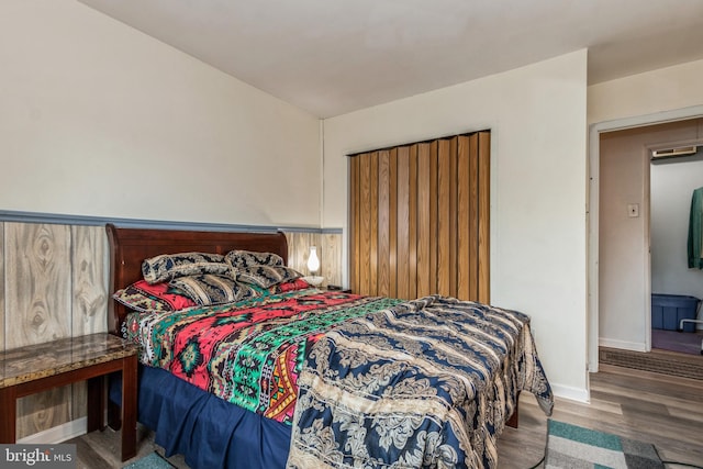 bedroom featuring wainscoting, wood finished floors, and baseboards