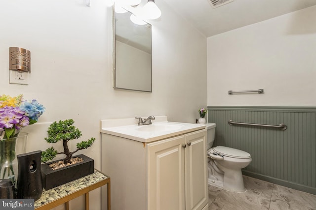 bathroom with visible vents, wainscoting, vanity, and toilet