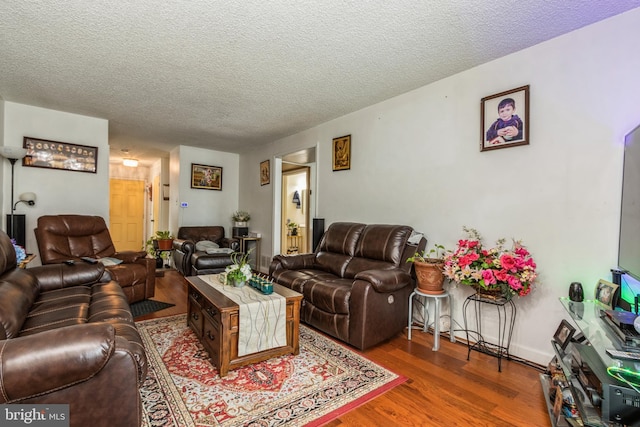 living room featuring a textured ceiling, wood finished floors, and baseboards