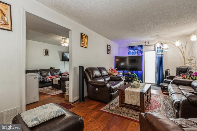 living area featuring a textured ceiling, wood finished floors, and visible vents