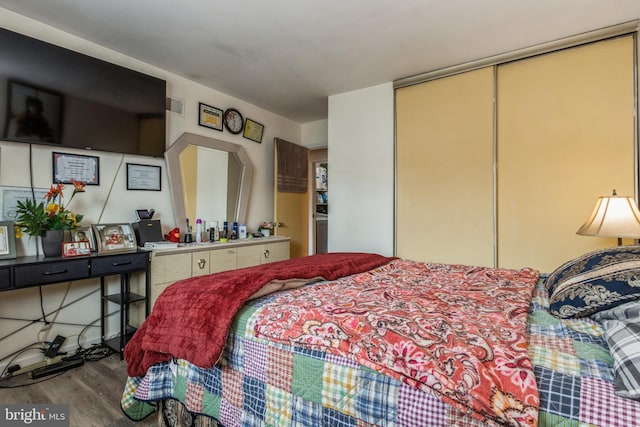 bedroom with a closet, visible vents, and wood finished floors