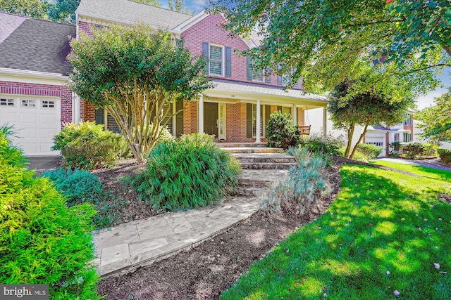 view of front of property with a garage, covered porch, a front lawn, and brick siding