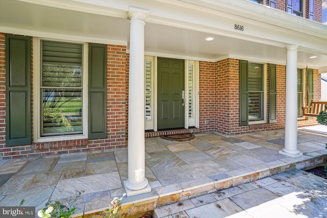 property entrance with covered porch and brick siding