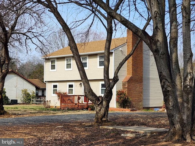 view of front of property featuring cooling unit, a shingled roof, crawl space, a wooden deck, and a chimney