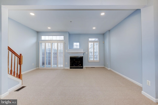 unfurnished living room with carpet floors, baseboards, stairway, and recessed lighting