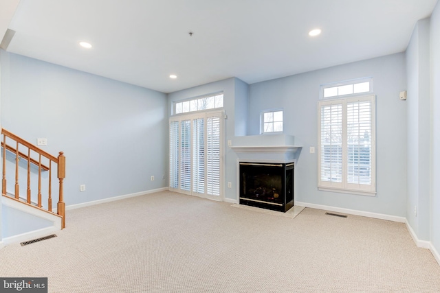 unfurnished living room featuring recessed lighting, visible vents, stairway, a fireplace with flush hearth, and baseboards