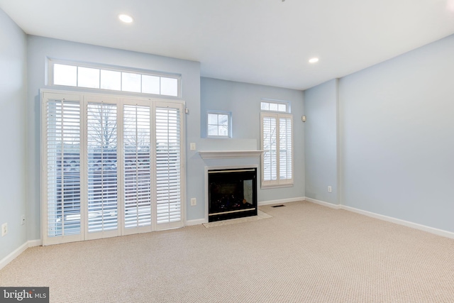 unfurnished living room featuring baseboards, carpet, a fireplace with flush hearth, and recessed lighting