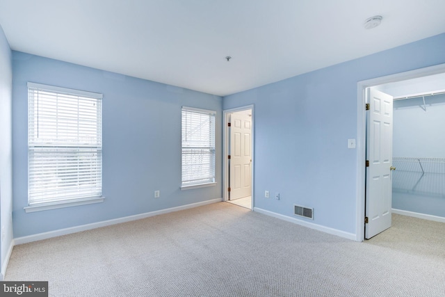 unfurnished bedroom with visible vents, baseboards, a closet, carpet, and a walk in closet