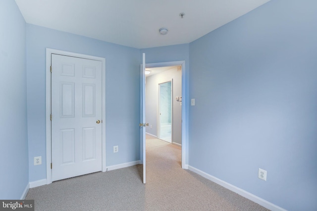 unfurnished bedroom featuring light colored carpet and baseboards