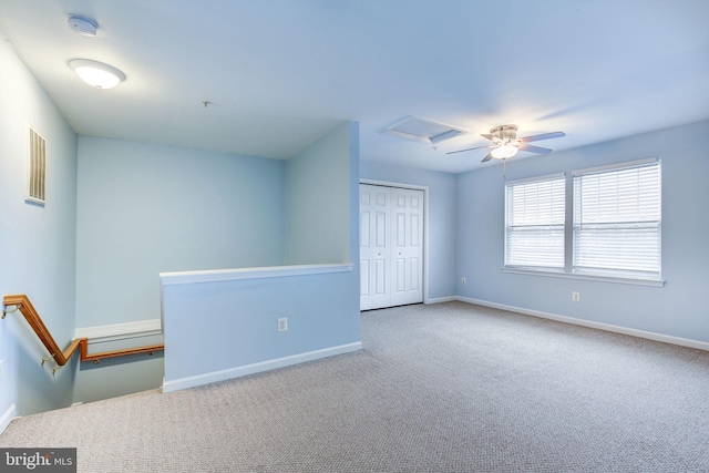 spare room featuring ceiling fan, carpet, attic access, and baseboards