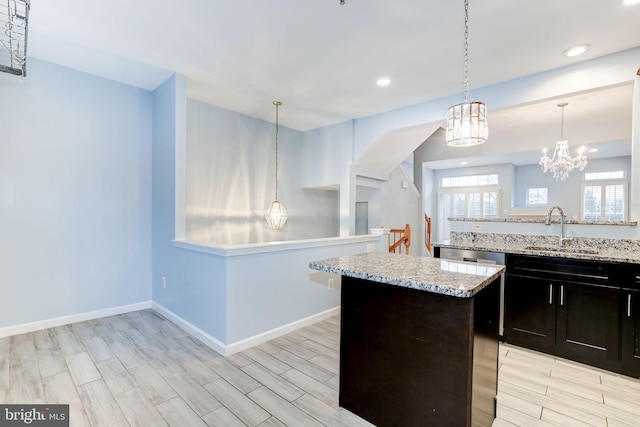 kitchen with light stone counters, a kitchen island, a sink, baseboards, and wood tiled floor