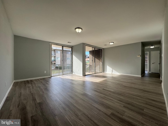 unfurnished living room featuring baseboards, dark wood-style floors, and floor to ceiling windows