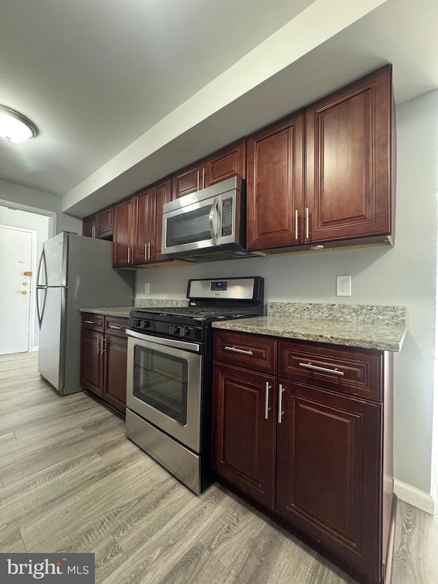 kitchen with light stone counters, baseboards, light wood-style floors, and appliances with stainless steel finishes