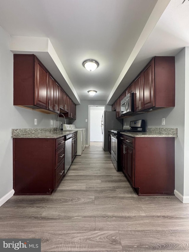 kitchen featuring washer / dryer, baseboards, light wood finished floors, and stainless steel appliances