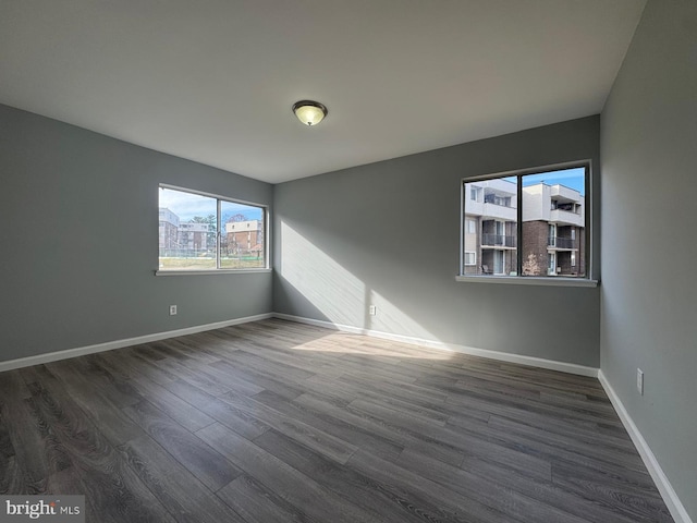 spare room featuring baseboards and dark wood-style flooring