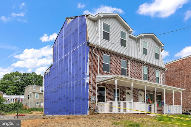 multi unit property featuring a porch and brick siding