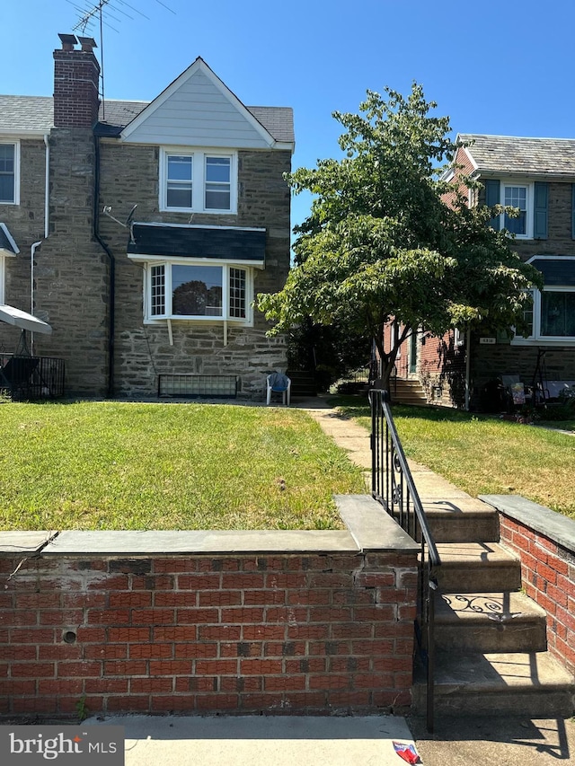 view of front of house featuring stone siding and a front yard