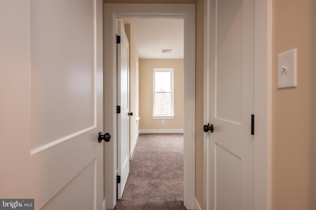 hall with visible vents, baseboards, and dark colored carpet