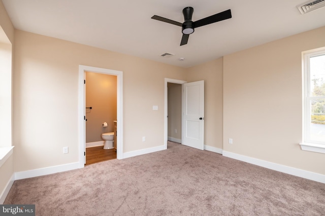 unfurnished bedroom with ensuite bath, baseboards, visible vents, and carpet flooring