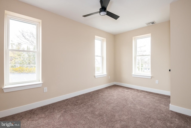 carpeted spare room with a ceiling fan, visible vents, and baseboards