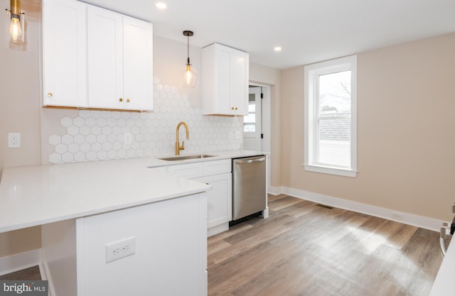 kitchen with tasteful backsplash, light wood-style flooring, stainless steel dishwasher, white cabinets, and a sink