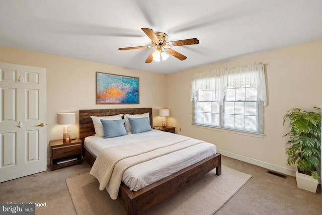 bedroom with visible vents, baseboards, light colored carpet, and a ceiling fan