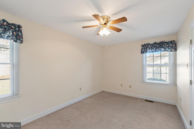 unfurnished room with light colored carpet, baseboards, visible vents, and ceiling fan