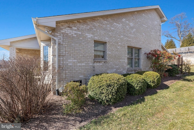 view of property exterior with brick siding and a lawn