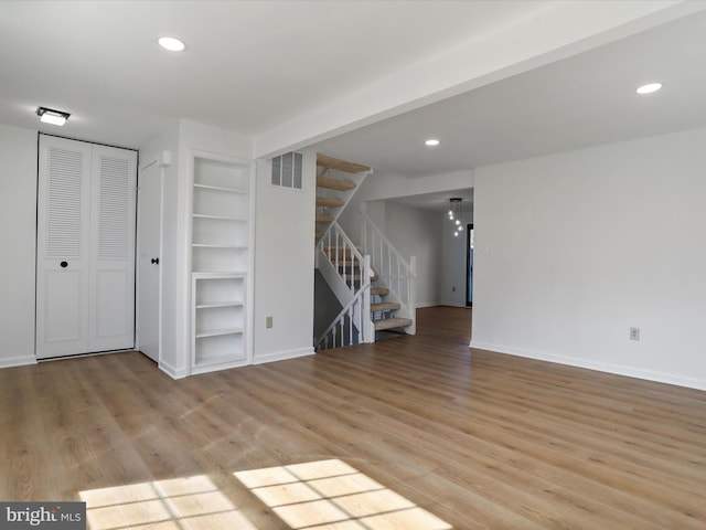 interior space featuring visible vents, built in shelves, baseboards, stairway, and wood finished floors