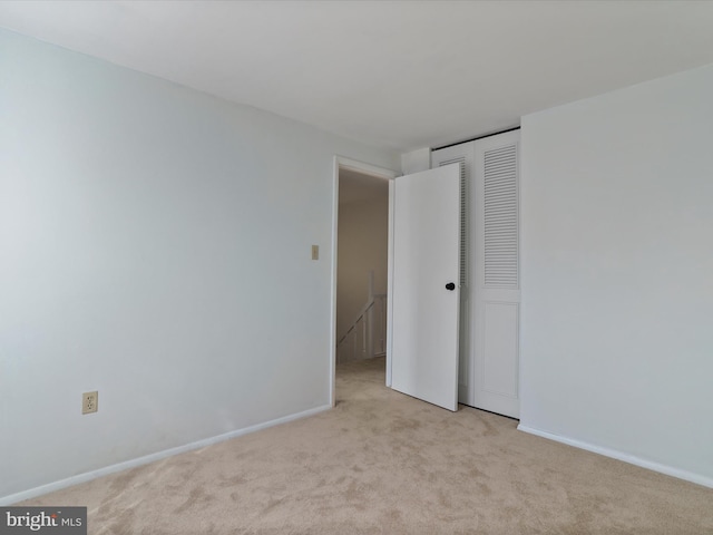 spare room with baseboards and light carpet