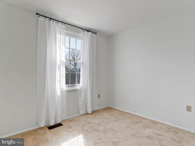 carpeted spare room with visible vents and baseboards