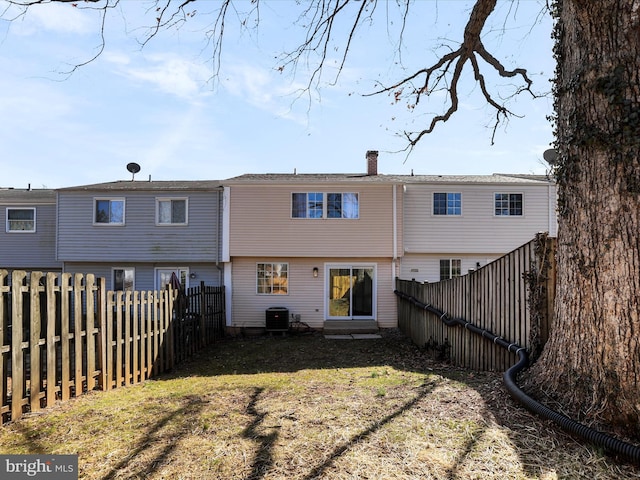 rear view of house with a fenced backyard, a lawn, central AC, and a chimney