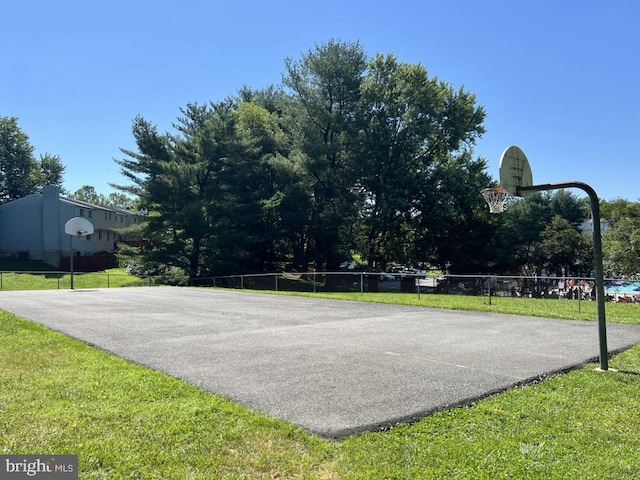 view of basketball court with community basketball court, a lawn, and fence