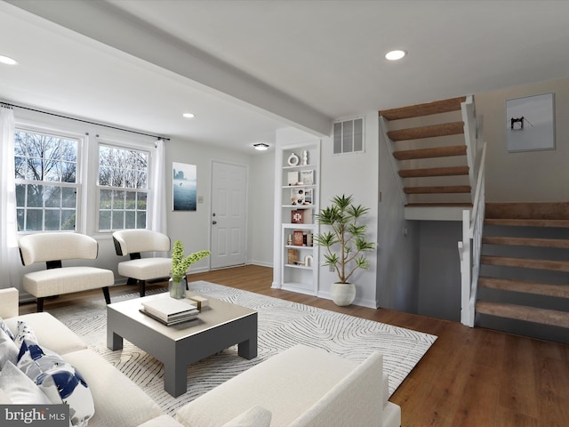 living room with recessed lighting, visible vents, wood finished floors, and stairway