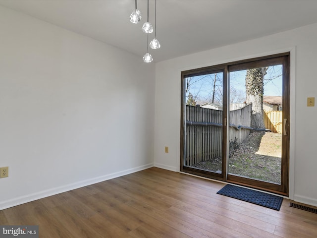 unfurnished dining area featuring visible vents, baseboards, and wood finished floors