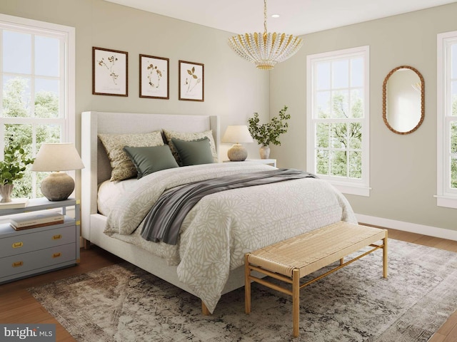 bedroom with an inviting chandelier, baseboards, and wood finished floors