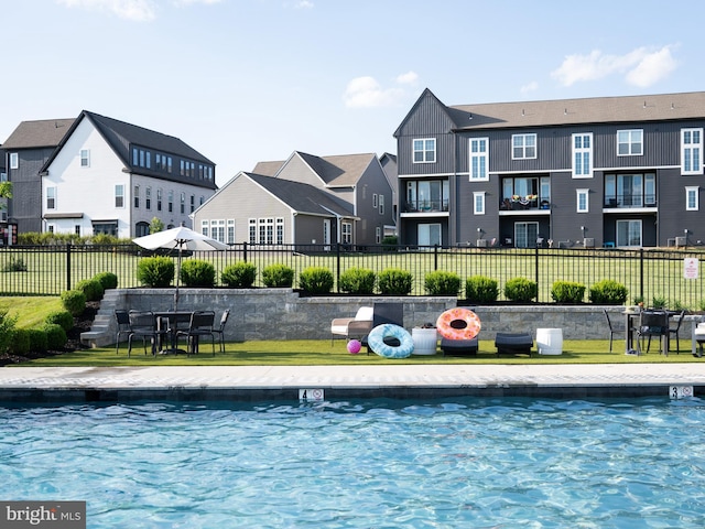 community pool with a lawn, fence, and a residential view