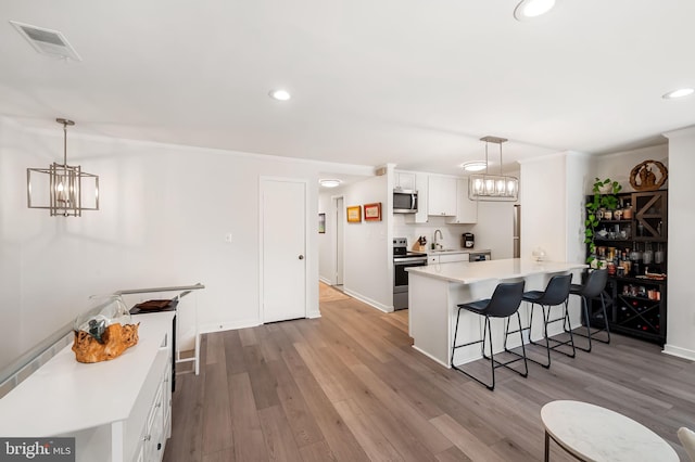 kitchen featuring visible vents, white cabinets, stainless steel appliances, light countertops, and a notable chandelier