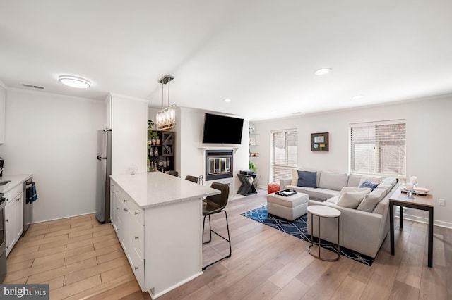 kitchen with stainless steel appliances, white cabinetry, a peninsula, and a kitchen bar