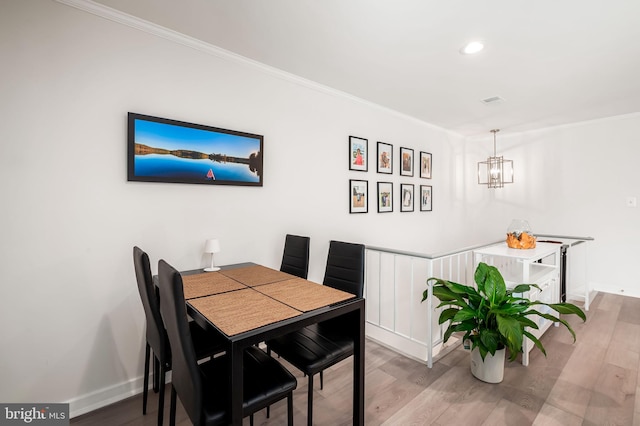 dining space featuring a chandelier, recessed lighting, wood finished floors, baseboards, and ornamental molding