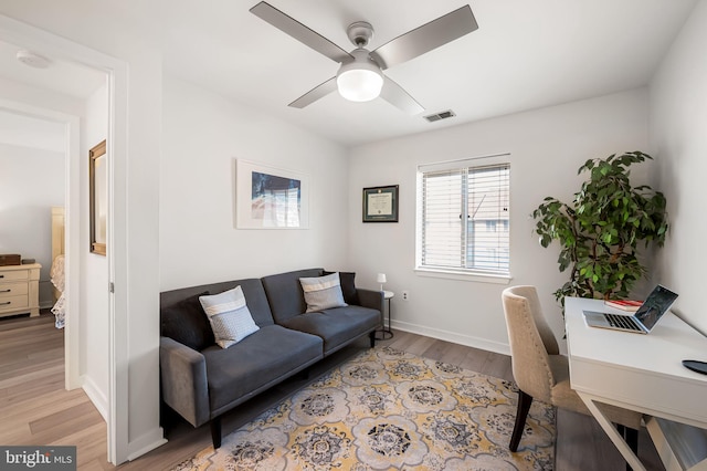 home office featuring light wood-style flooring, visible vents, ceiling fan, and baseboards